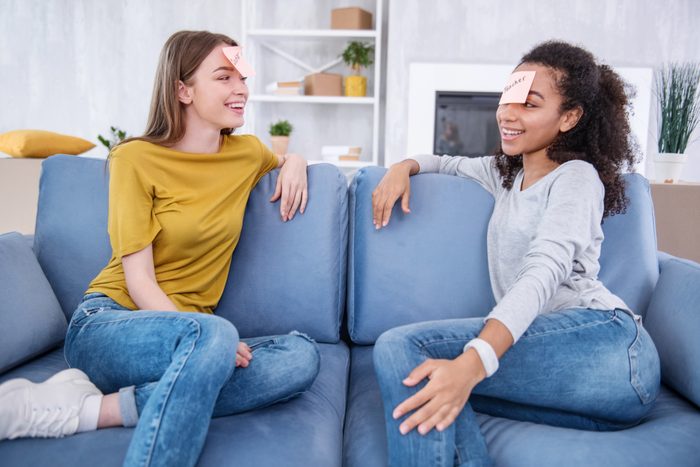 two girl friends playing heads up on a couch