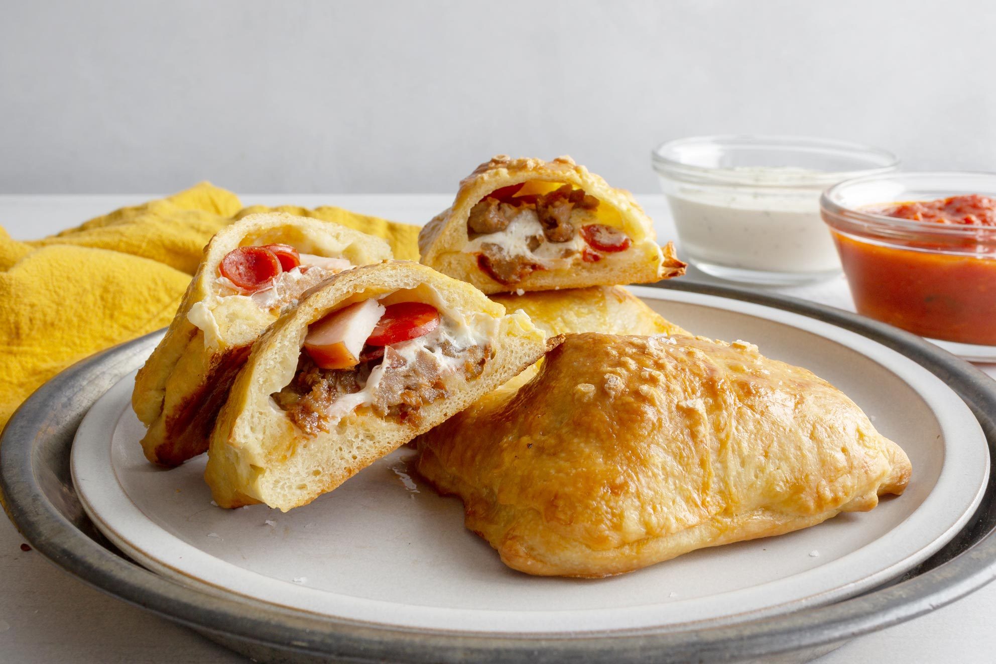 close up of Pioneer woman pizza pockets on a plate with a yellow napkin and dipping sauces to the side