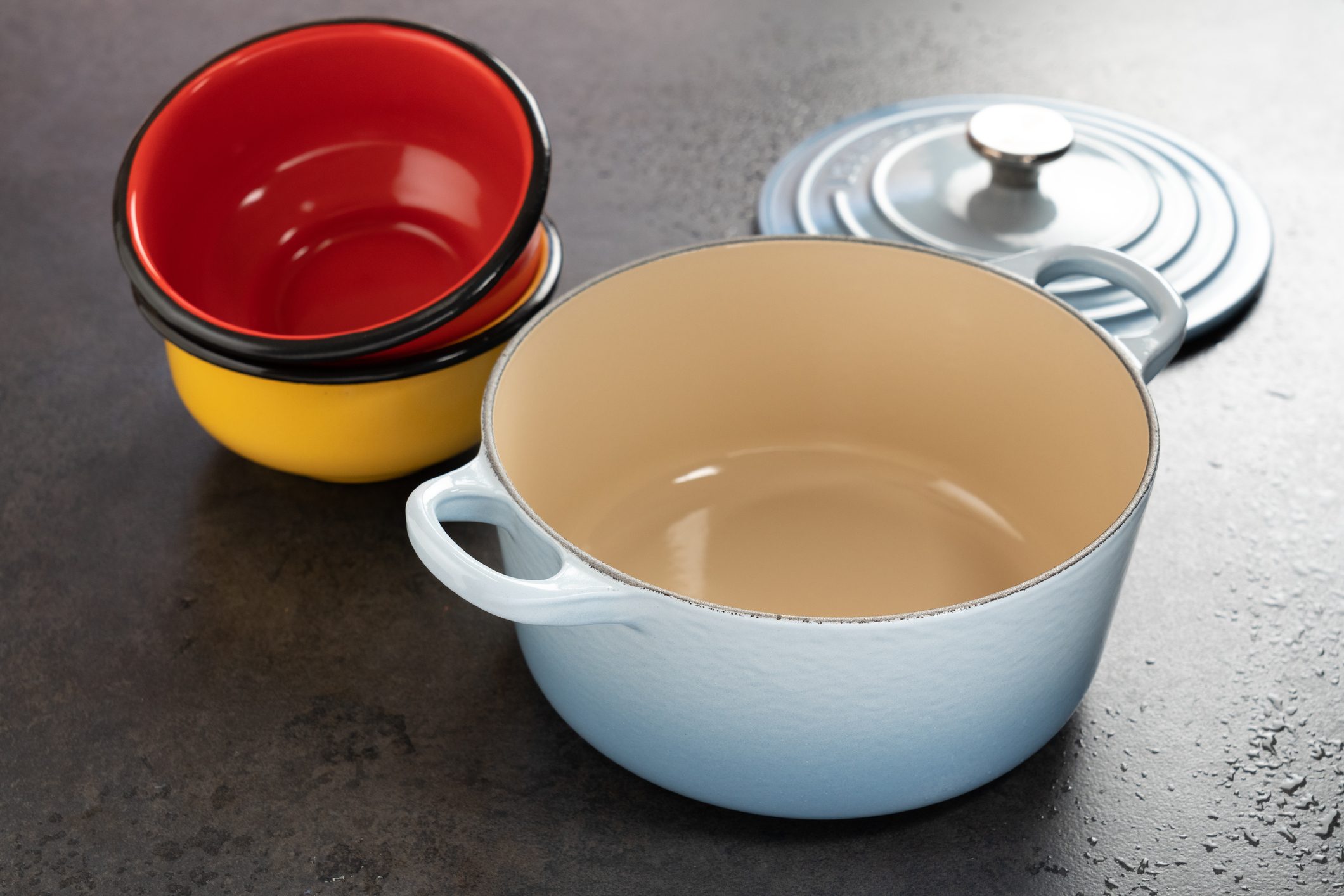 Dutch oven and enameled pewter on a black surface.