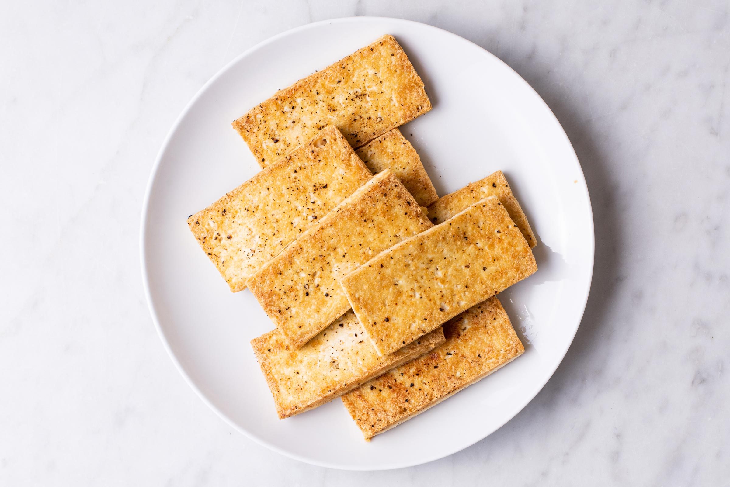 seared tofu on a white plate, top view