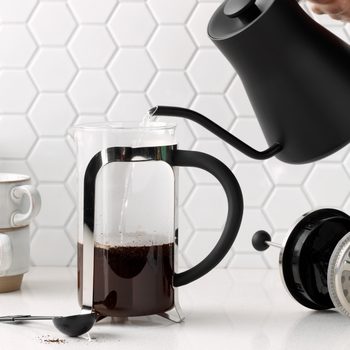 pouring water into a French press from a black goose neck kettle