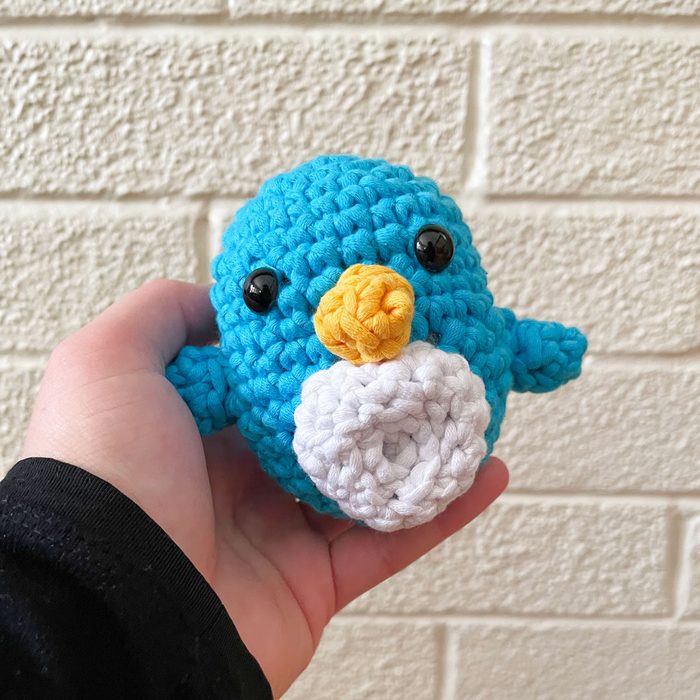 Woobles Crochet Kit finished product Pierre the Penguin being held in a person