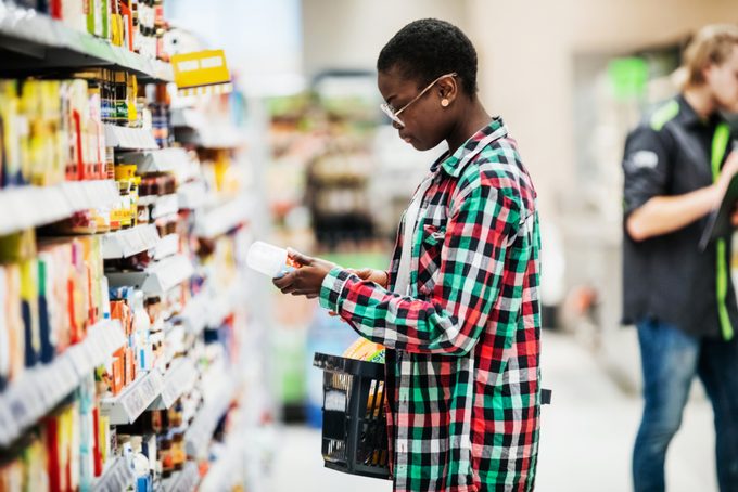 Young Woman Reading Label On Food Item In Supermarket