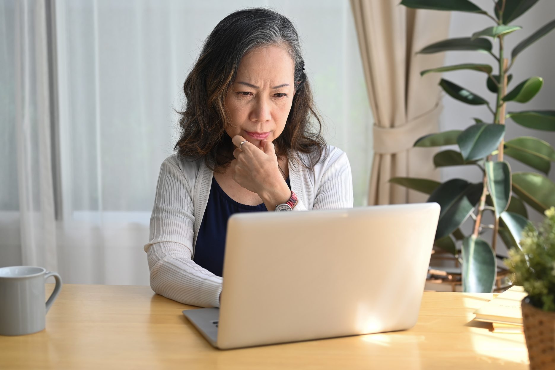 Serious mature woman checking business email during remote working from home.