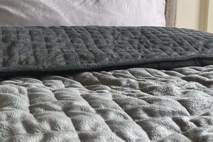 Still life of gray, weighted, blanket in bedroom