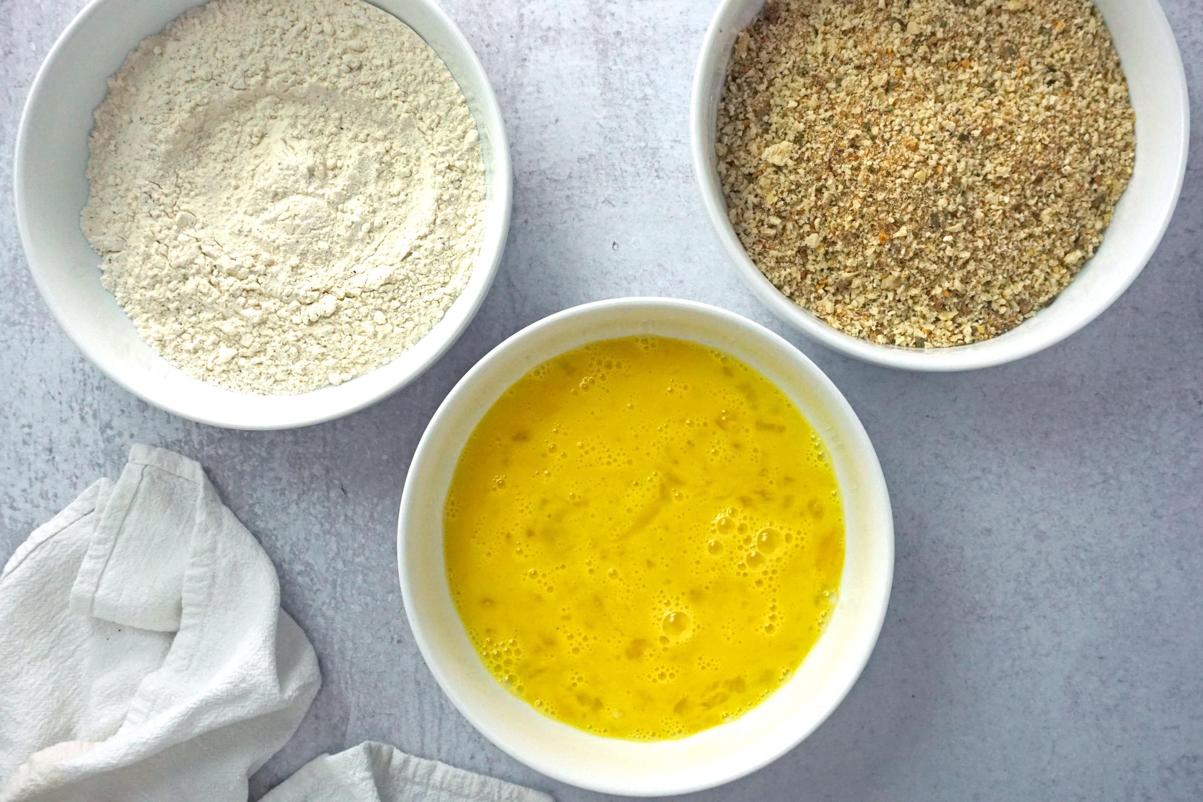 three bowls with ingredients for coating Mozzarella Sticks before frying