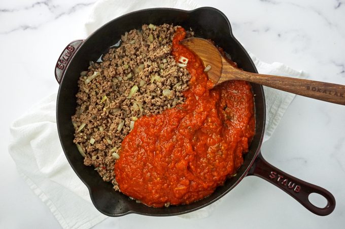 red sauce and cooked beef in a cast iron skillet