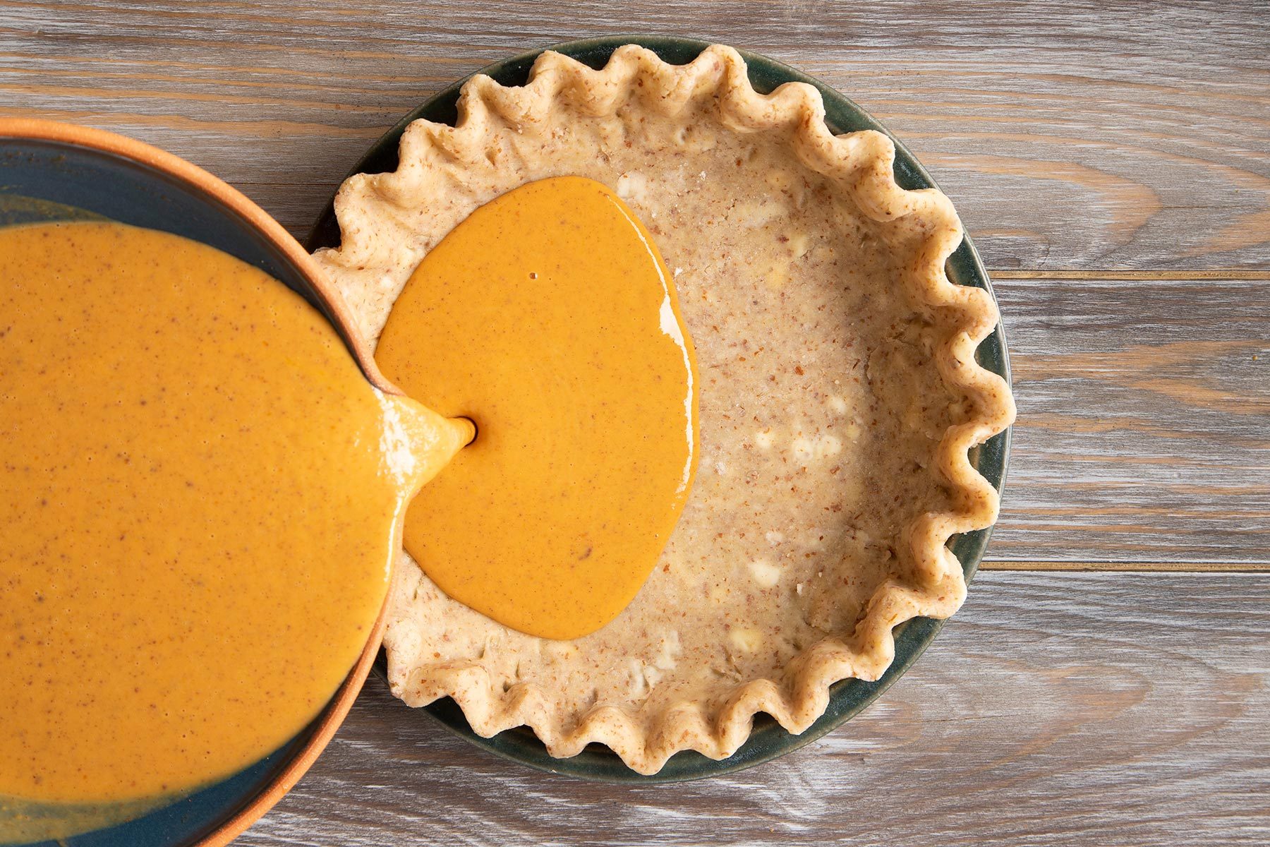 Pouring pumpkin pie mix on the dough