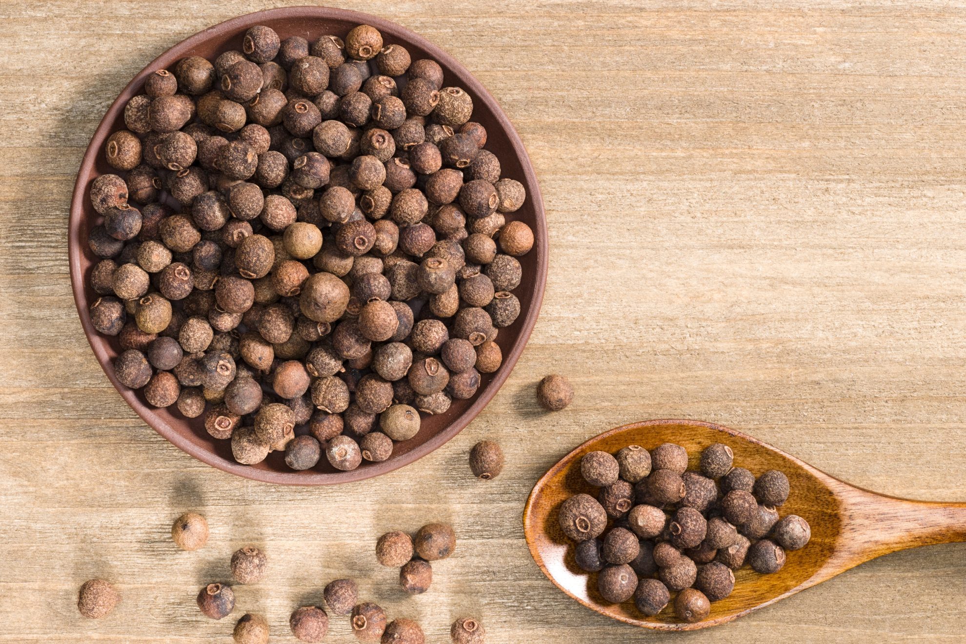 Allspice in clay plate and spoon