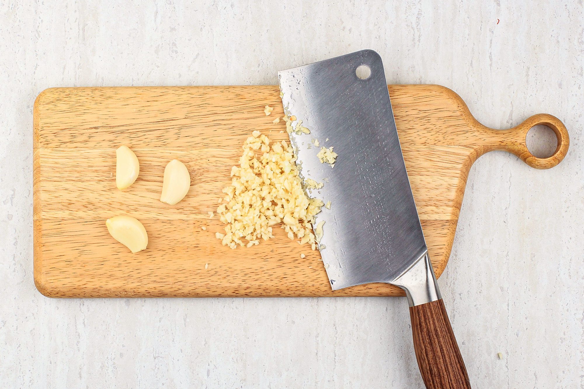 Chopped Garlic On The Wooden Chopping Board With Chopper Knife