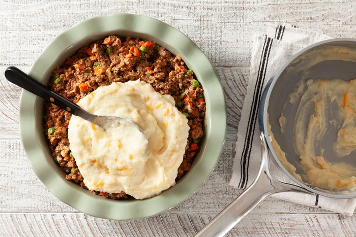 Layering mashed potato over meat mixture