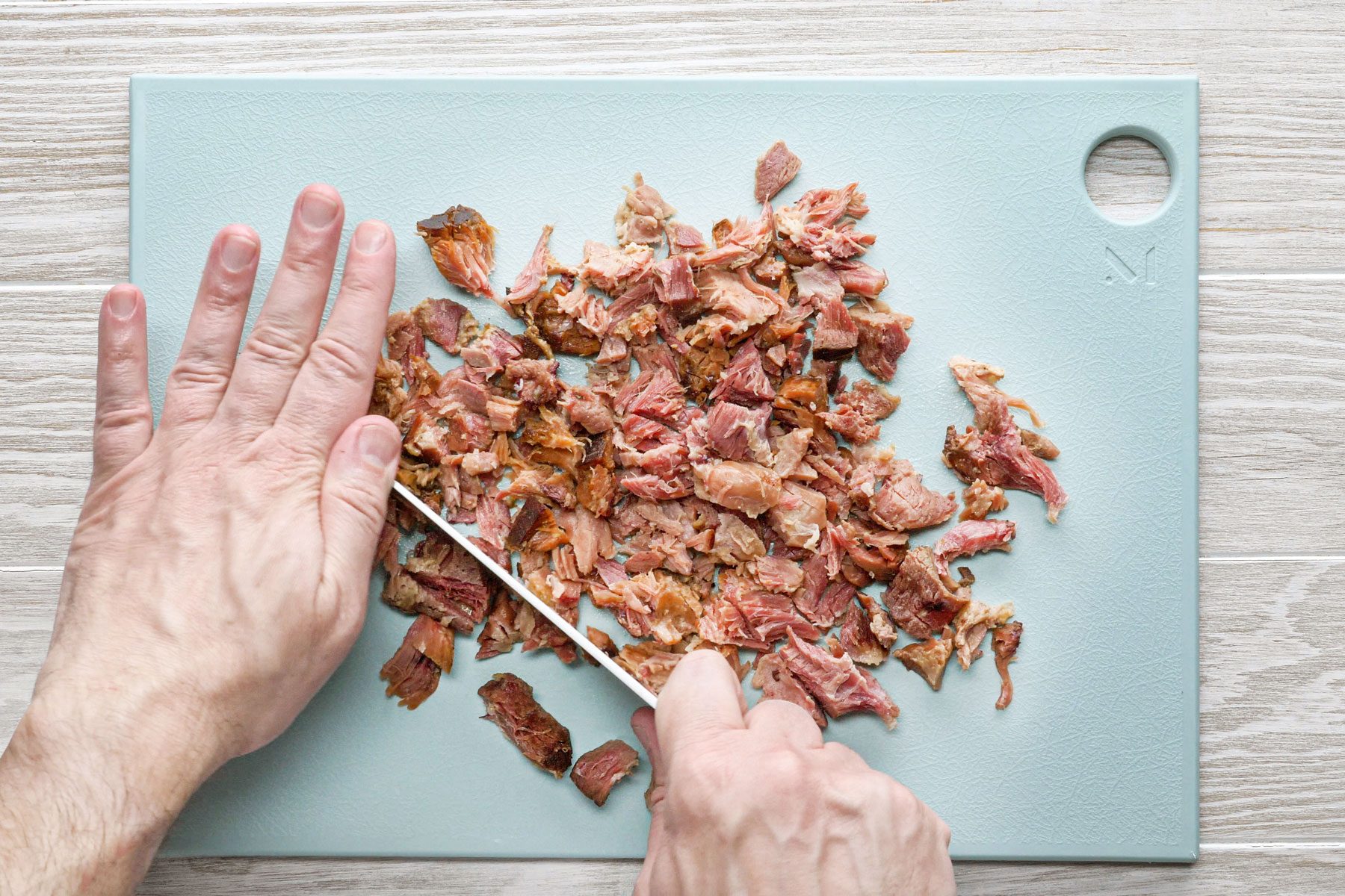 Copping ham with a knife on a tray