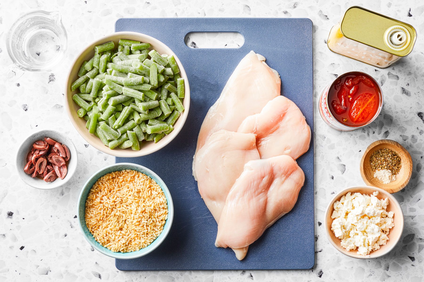 Chicken breasts Greek olives Stewed tomatoes and other ingredients on a countertop