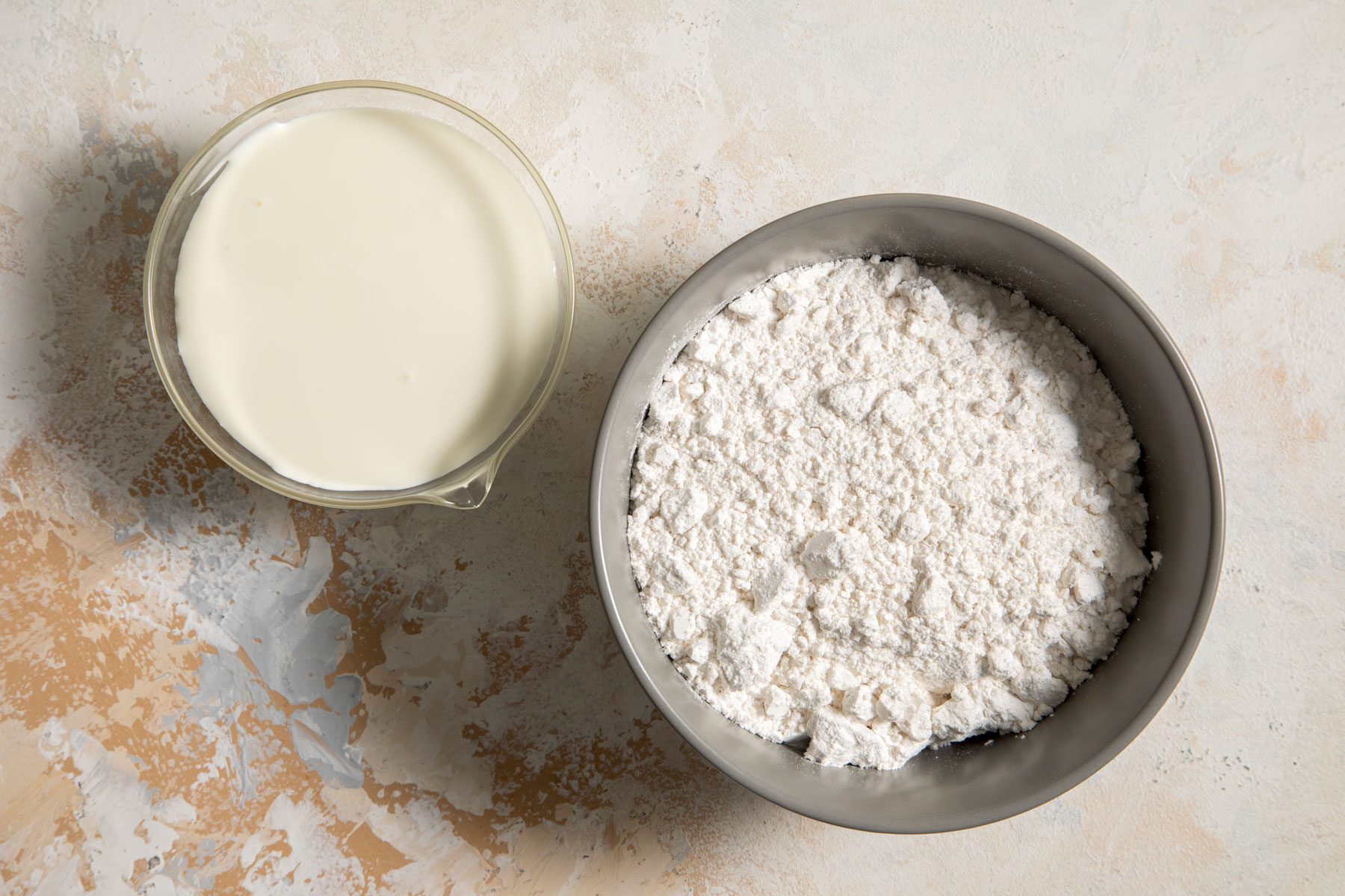 Self-rising flour and heavy whipping cream placed on a marble surface
