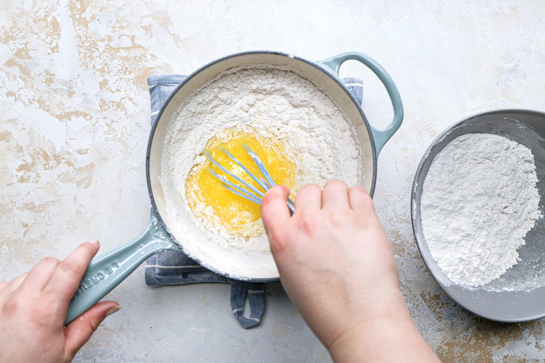 Adding the four into the egg mixture in a large saucepan.