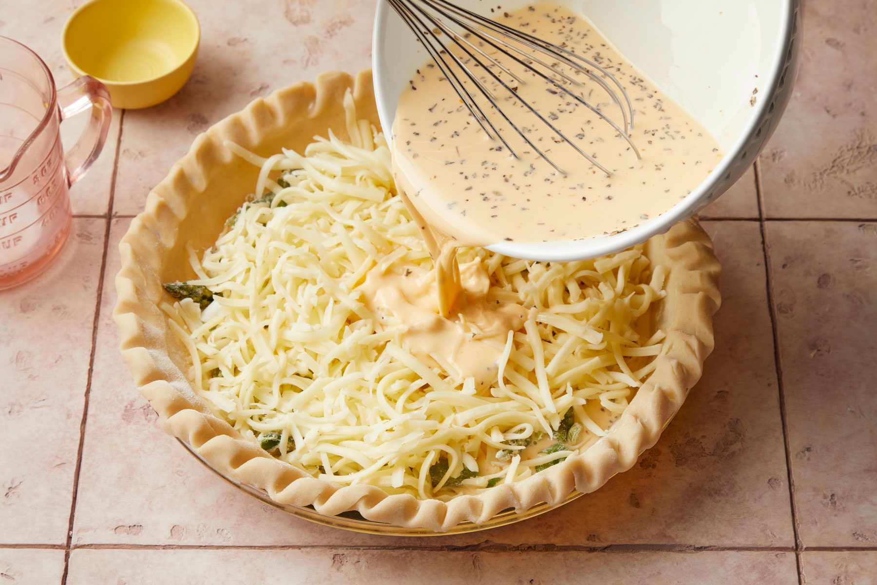 Pouring the eggs and cream mixture in pie crust with cheese