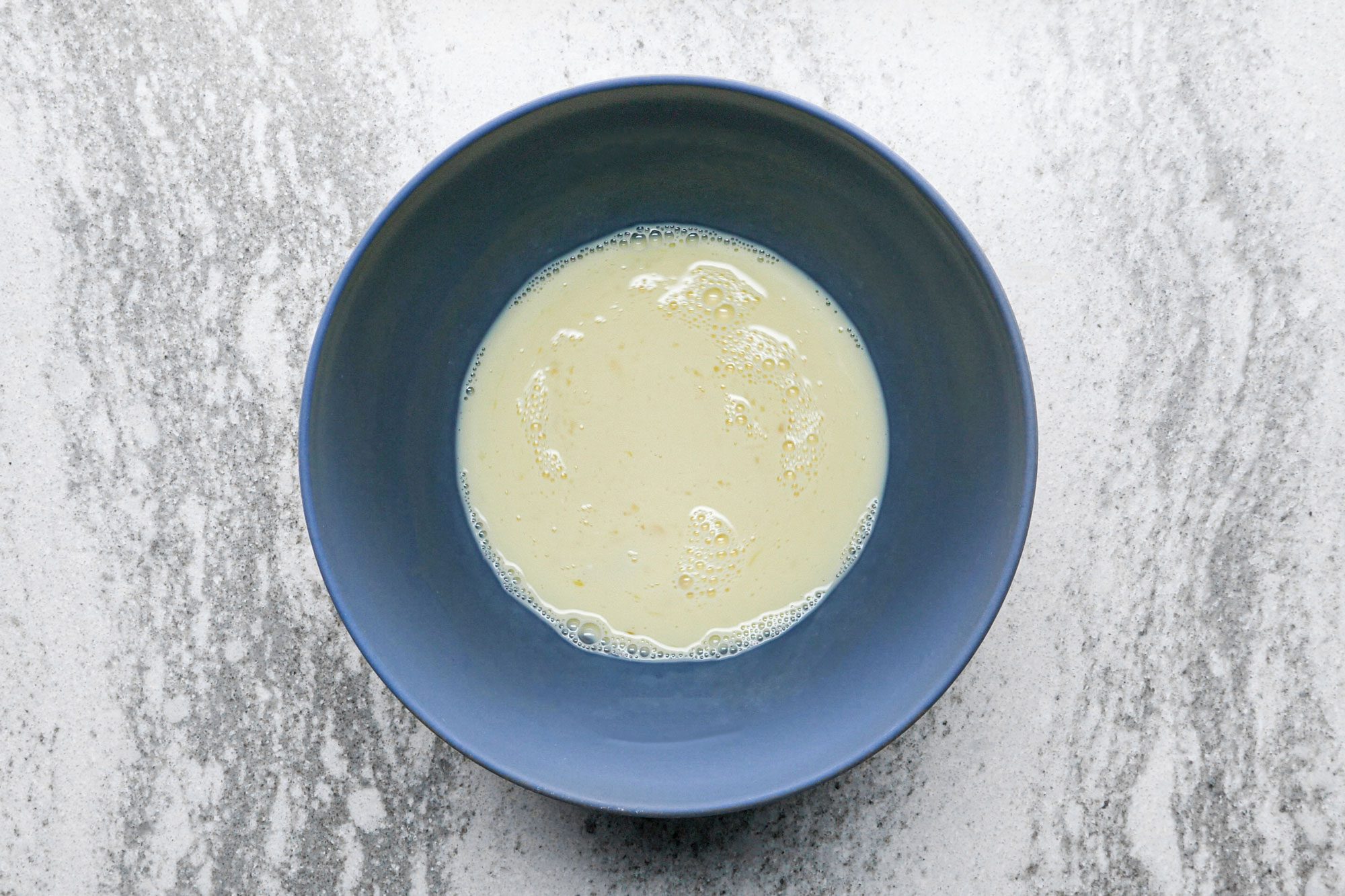 egg and milk mixture in a bowl on marble surface