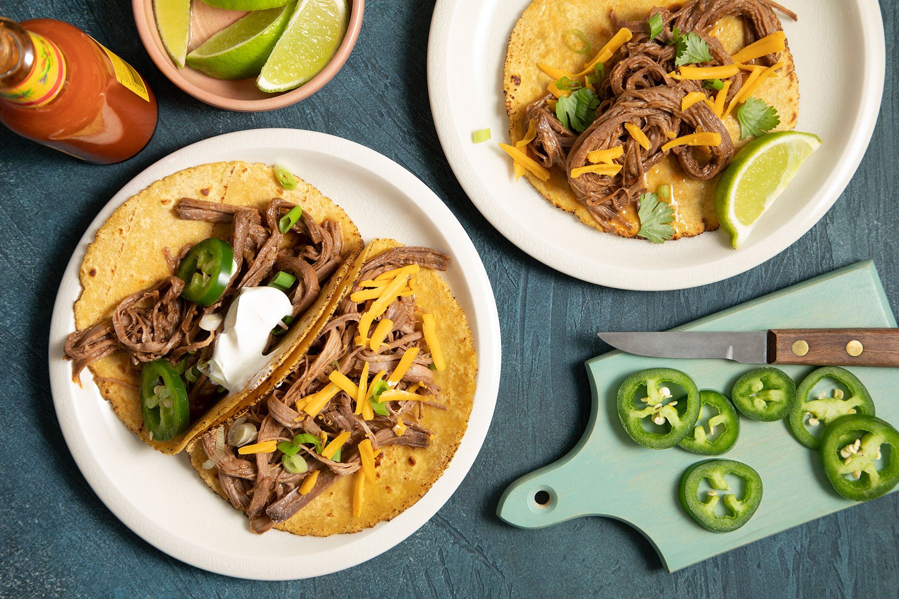 Brisket Tacos topped with lemon, jalapeños and cheese and served on plate 
