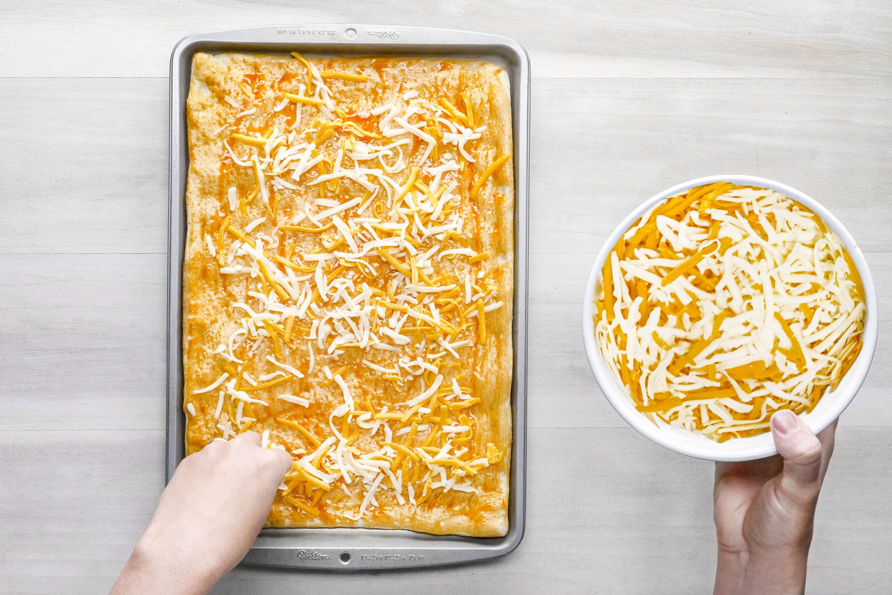 Buffalo wing sauce brushed with cheese over the dough in a backing pan