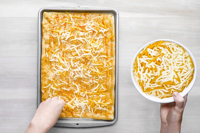 Buffalo wing sauce brushed with cheese over the dough in a backing pan