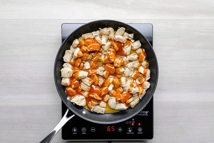 Chicken pieces with Buffalo wing sauce cooked in a pan