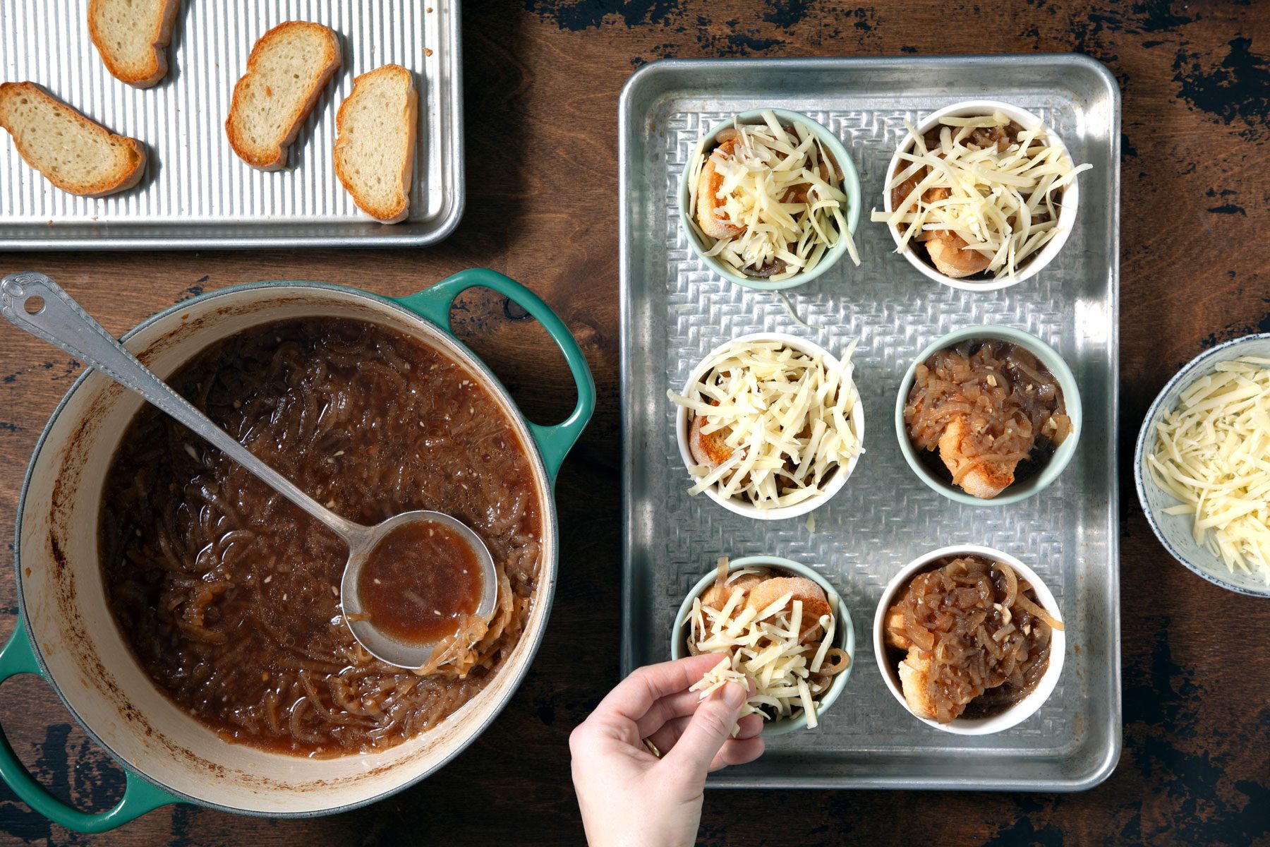Topping the cheese over the toast and onion soup inside small cups