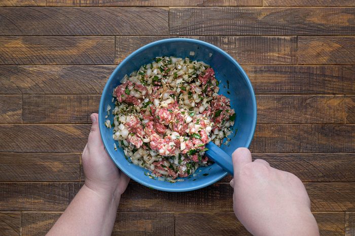 Onion, broth, uncooked rice and other ingredients mixed in a bowl