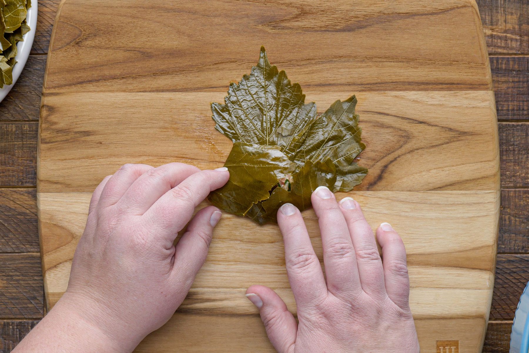 Folding in the sides of the leaf with beef mixture on a wooden table