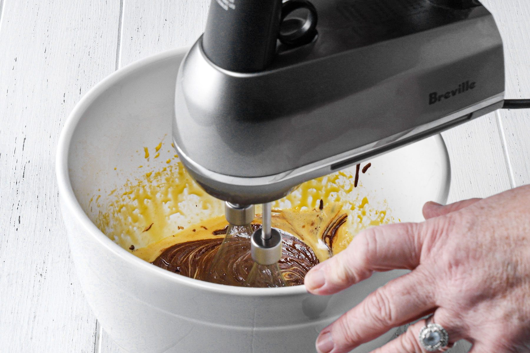 Mixing melted chocolate in bowl with beaten egg yolks 