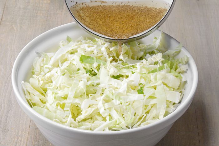 Mixing vinegar dressing in shredded into cabbage