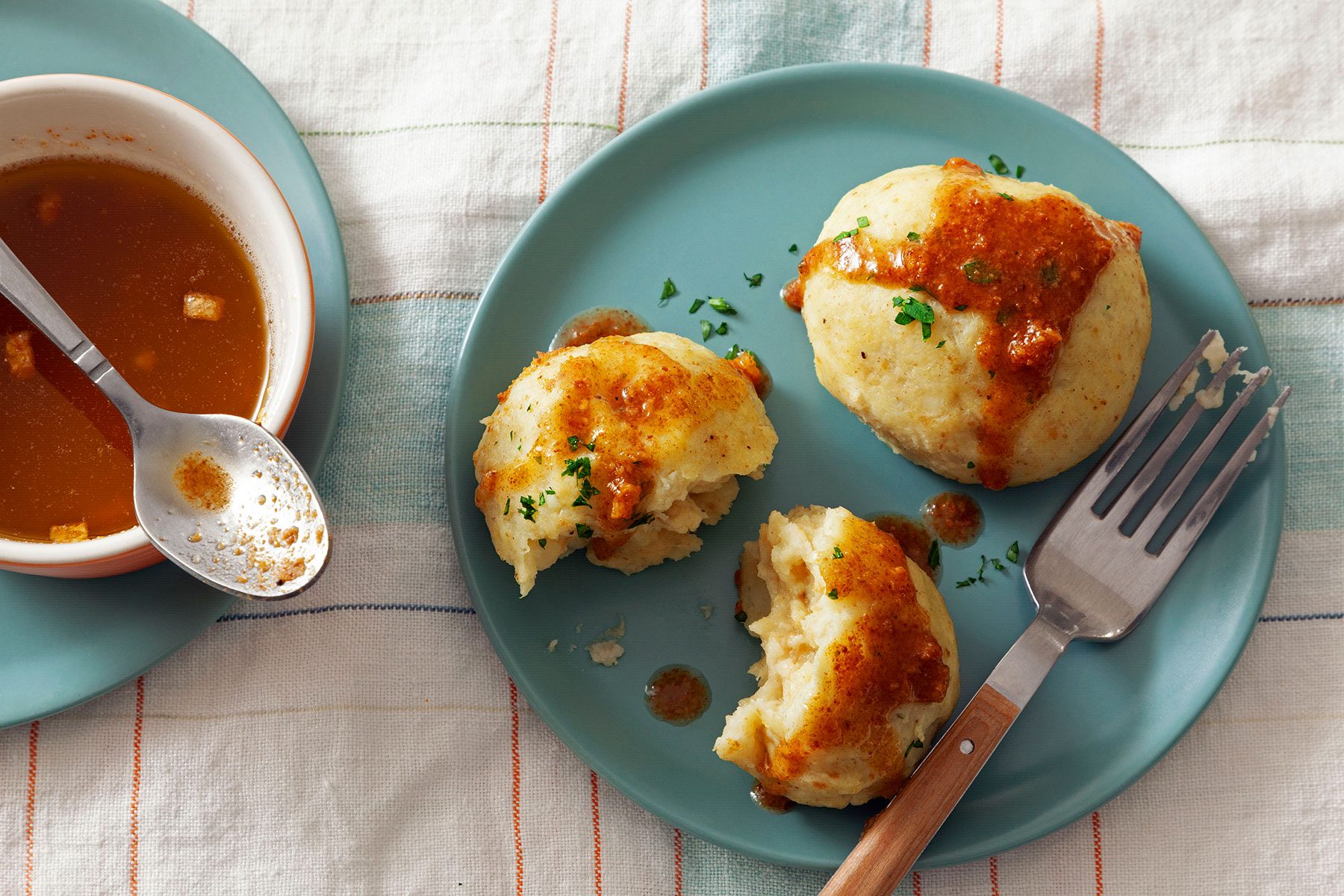German Potato served in green plate with fork and sauce on the side