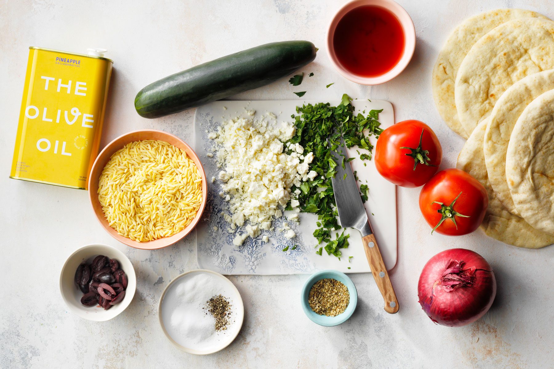 Orzo vegetables and other items placed on a marble kitchen countertop