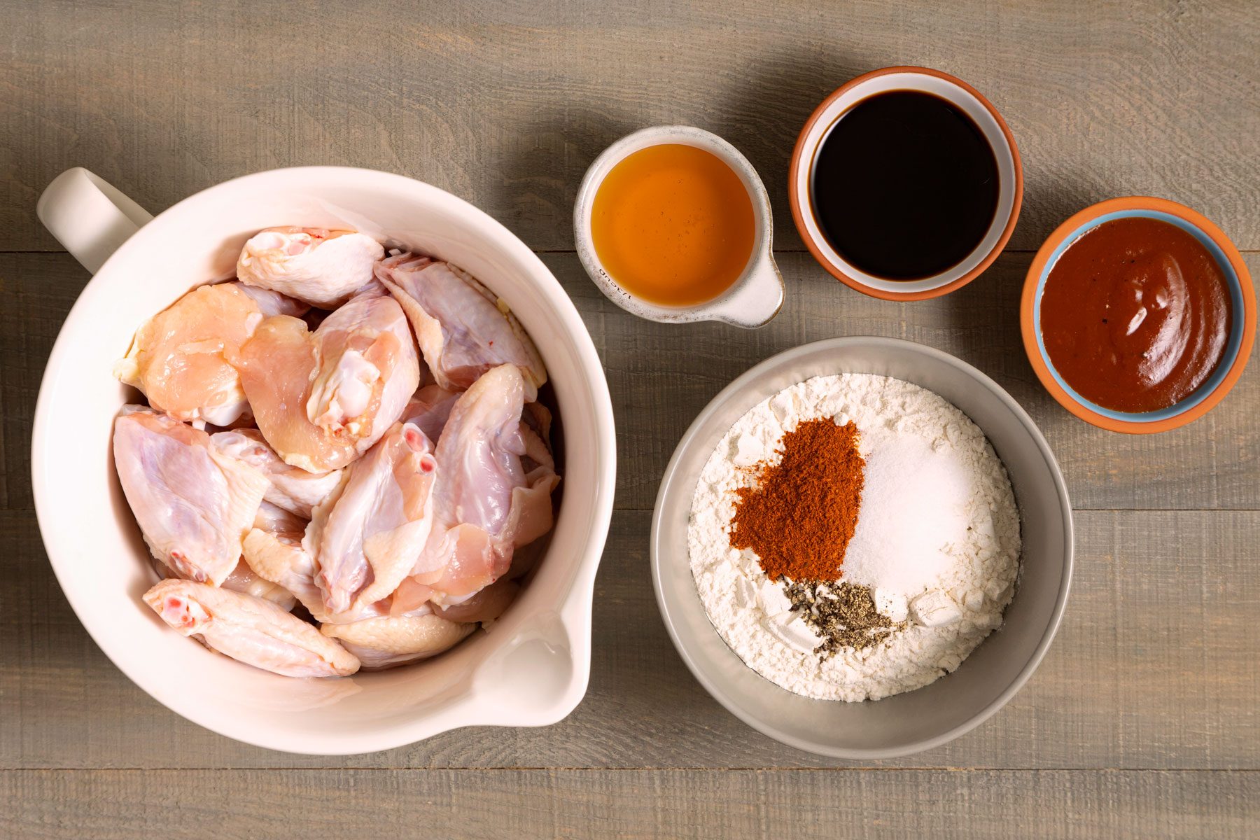 Chicken wings soya sauce honet flour and other ingredients on a wooden table