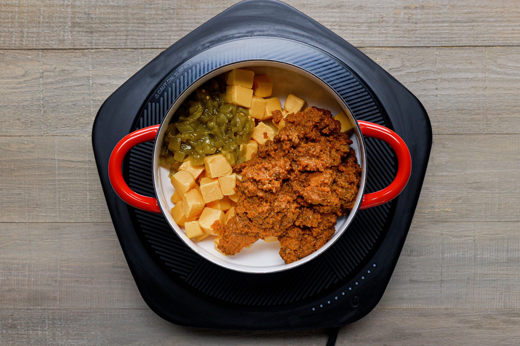 Cheese, chili con carne and chiles mixed in a saucepan