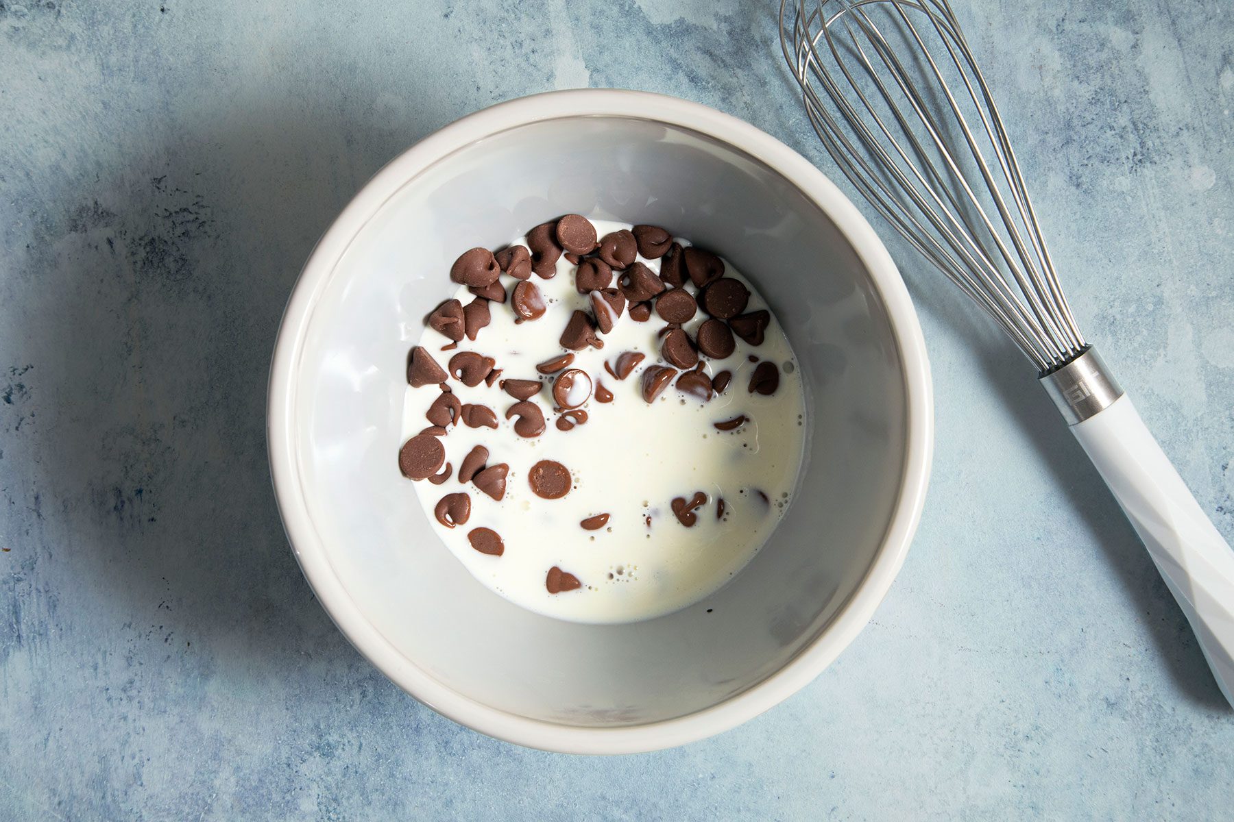 Whisking chocolate chips in small bowl filled with hot milk