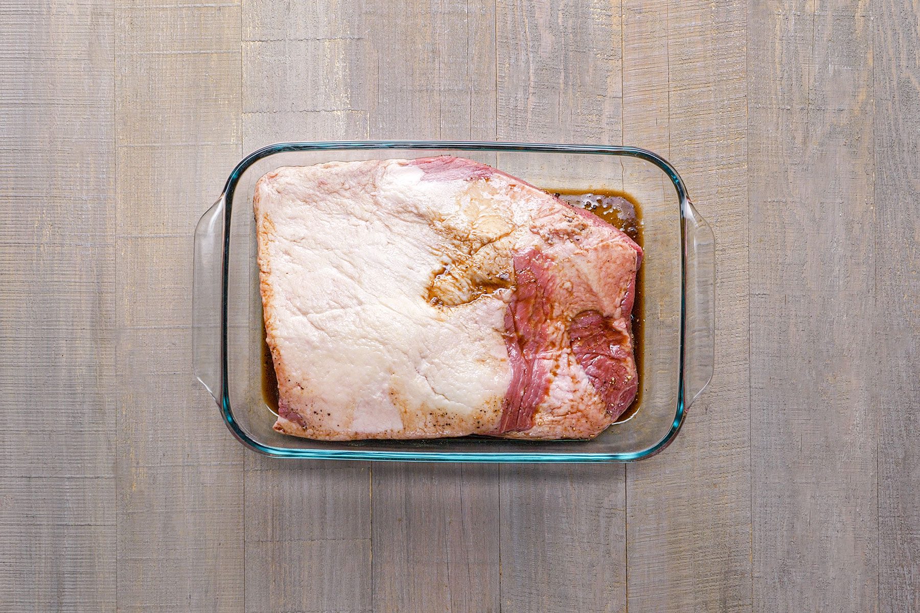 Seasoning the brisket in glass bowl