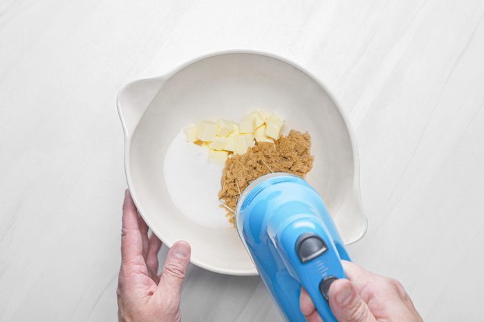 Beating the sugar and butter in a bowl with hand mixer