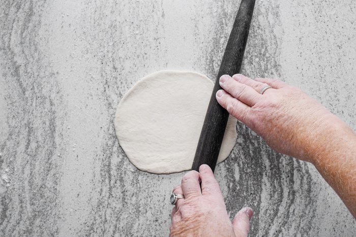 Rolling the dough into small circle shape on a countertop