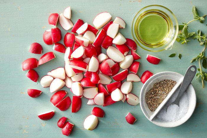 A pile of radishes and a bowl of oil