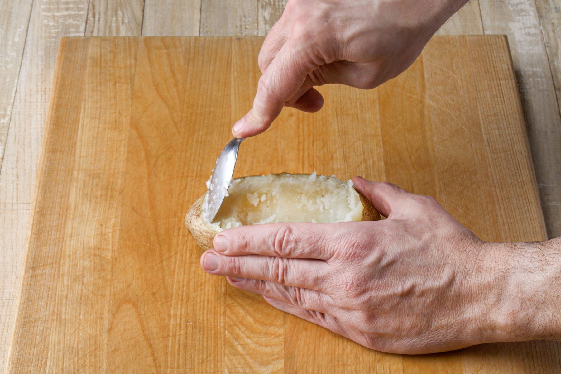Removing the pulp from a potato with a spoon