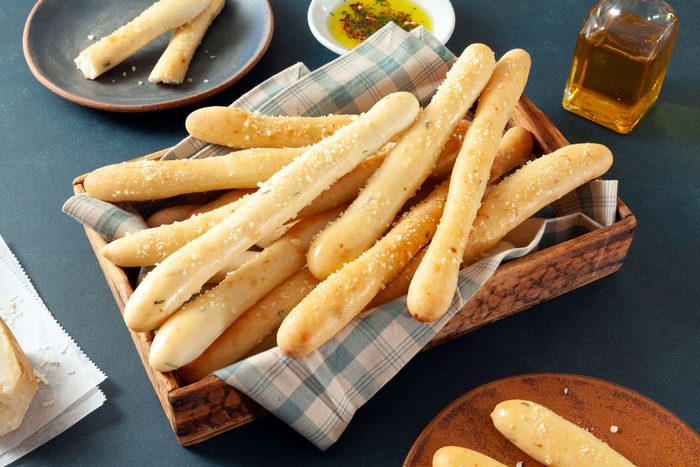 Soft Garlic Breadsticks Served in a Wooden Tray on Teal Surface