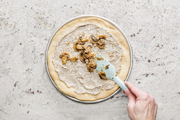 adding toppings to pizza