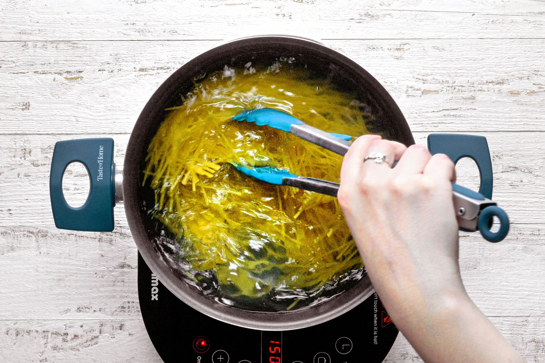 Cooking Spaghetti in a large pan on a wooden table