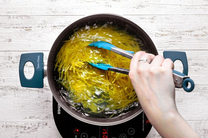 Cooking Spaghetti in a large pan on a wooden table