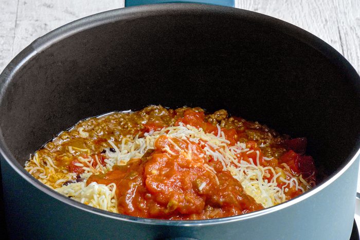 Tomatoes cheese and beef mixed inside a dutch oven