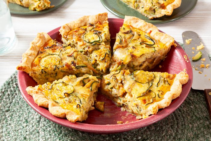 Zucchini Quiche in a Red Pie Plate on a Green Round Jute Rug