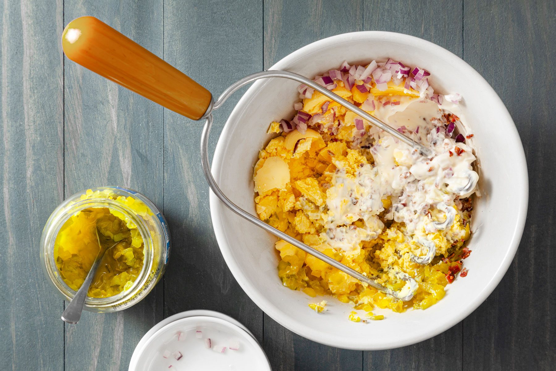Egg yolks onions and crumbled bacon mixed in small bowl