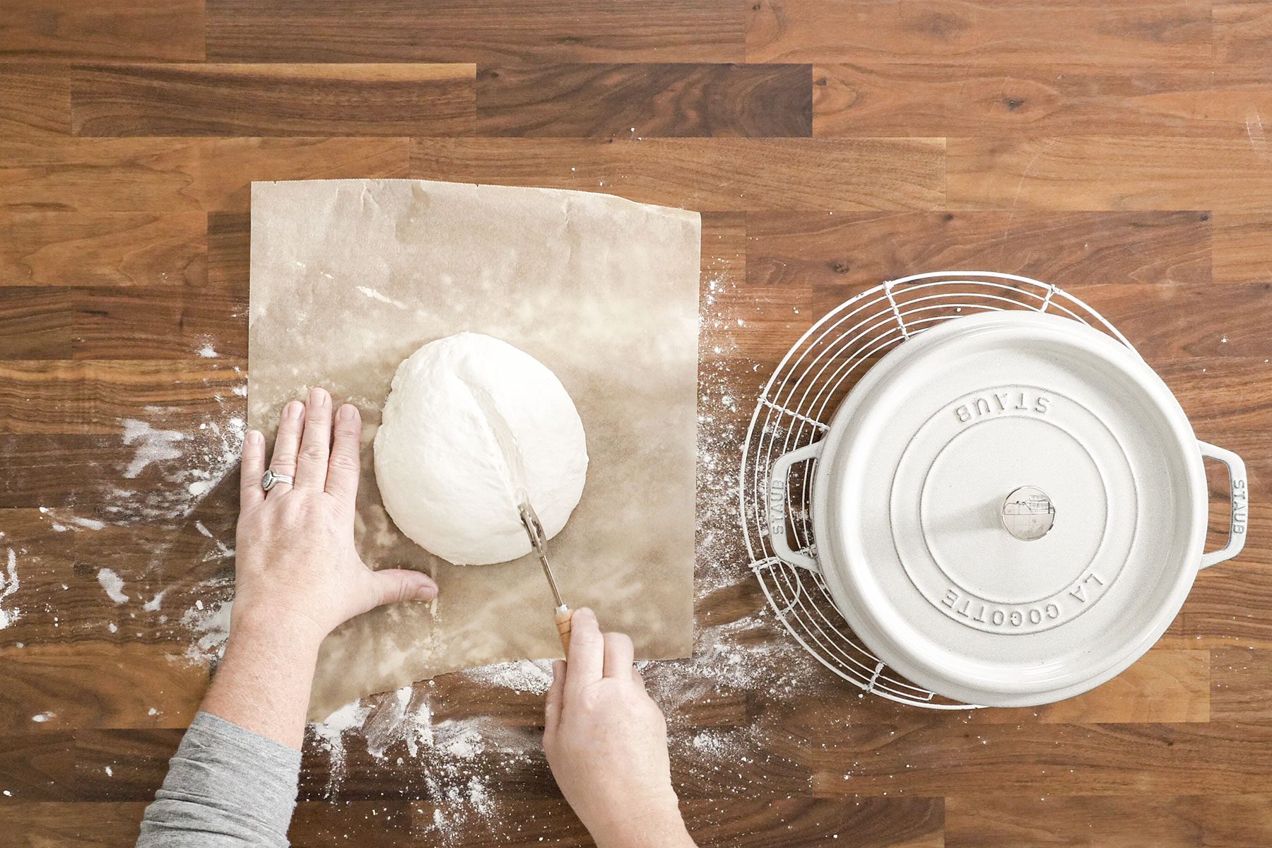 Slashing the dough with bread cutter on parchment paper