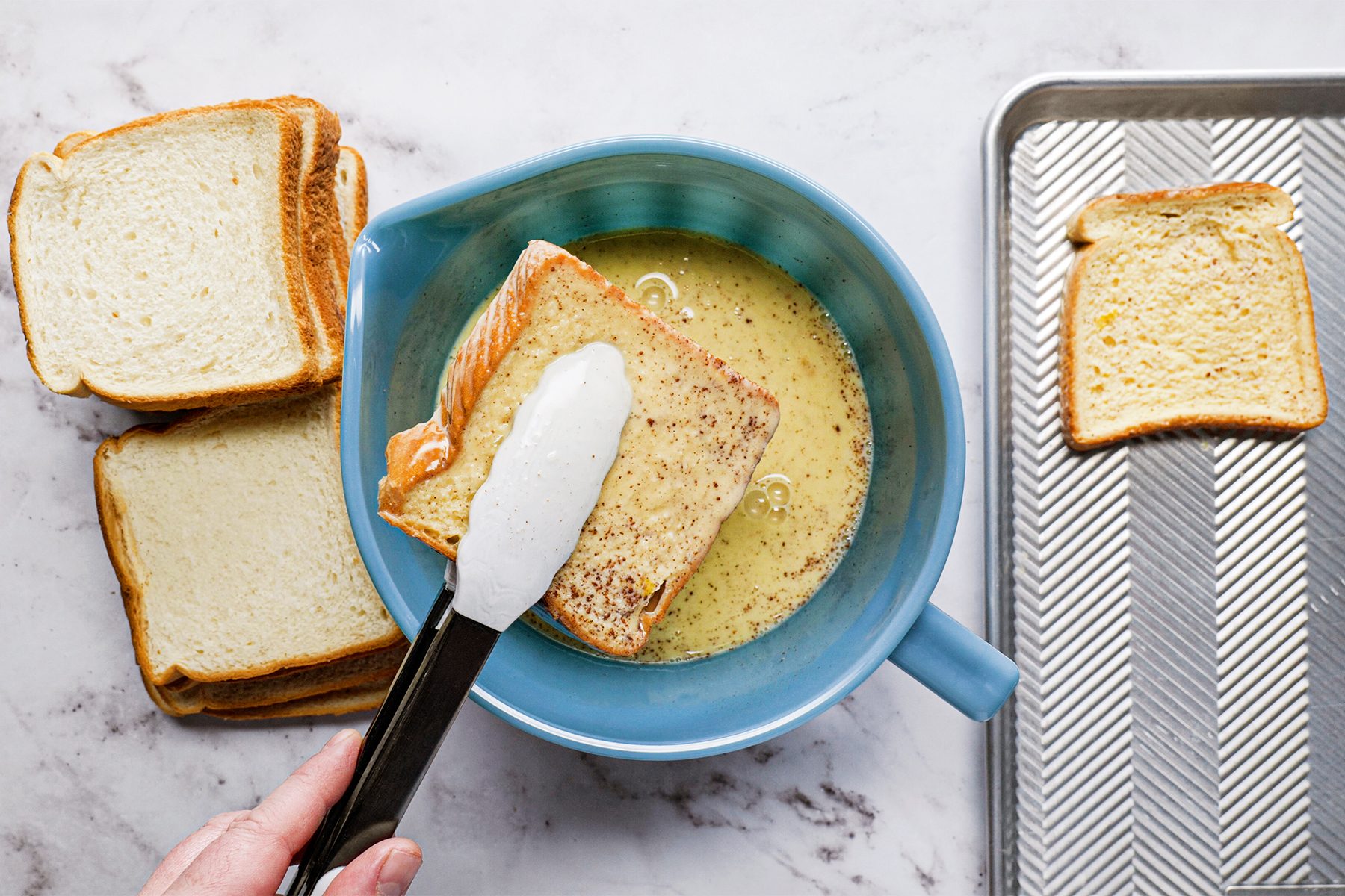 A person holding a knife over a bowl of bread, preparing to slice it for a meal