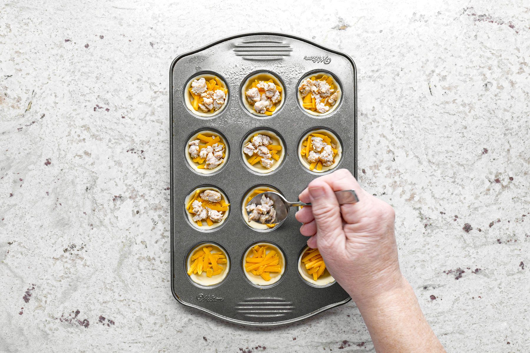 Adding chicken pieces to mini quiches